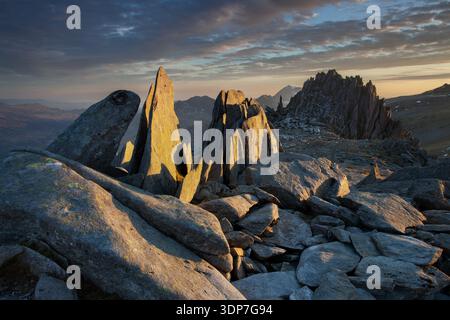 Ampio panorama montano nel Parco Nazionale di Snowdonia, Galles, con una calda luce serale sulle rocce in primo piano e colline a strati che sfumano in lontananza. Foto Stock