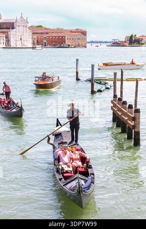 Un gondoliere che trasporta turisti dal Canal grande in uno stretto canale laterale a Venezia, Italia Foto Stock