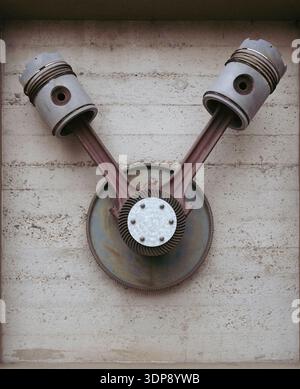 Un paio di vecchi pistoni sono montati su una parete. I pistoni sono arrugginiti e sembrano provenire da un motore d'epoca. Foto Stock
