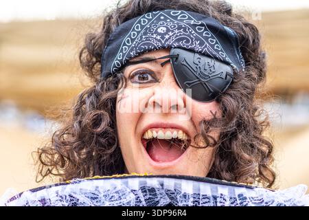 Donna vestita da pirata che indossa una bandana e un occhiello, che esprime un forte grido, celebra e si gode l'atmosfera festosa di una carn Foto Stock