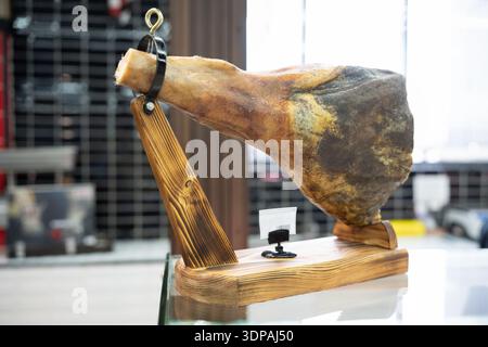 Prosciutto spagnolo su uno speciale stand di legno. Inceppamento intero in esposizione in un punto vendita . Foto Stock