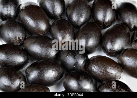 Mucchio di olive nere che brillano nella dispensa dello chef, il rivestimento a olio lucido evidenzia la consistenza, la composizione stretta suggerisce freschezza e uso culinario, id Foto Stock