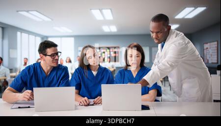 Studenti di medicina in classe universitaria imparare dal dottore su laptop. Foto Stock