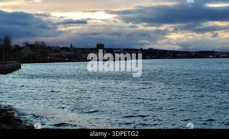 Una scena serale tempestosa sul Lago di Costanza con nuvole scure e una luce drammatica che attraversa il cielo coperto. Le onde guidate dal vento si spostano attraverso la Foto Stock