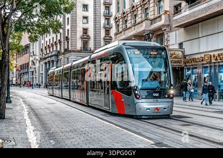Primo piano di un tram d'argento sui binari di Calle del coso vicino agli edifici storici. Trasporto pubblico sostenibile. Saragozza, Spagna - 29 novembre 2021 Foto Stock