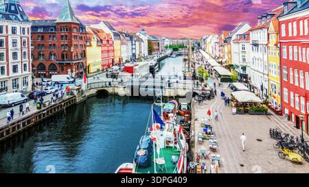 Stupendo cielo rosa al tramonto a Nyhavn (porto vecchio) - punto di riferimento a Copenhagen - con caffè e vecchie navi (storiche), barche a vela. Foto Stock