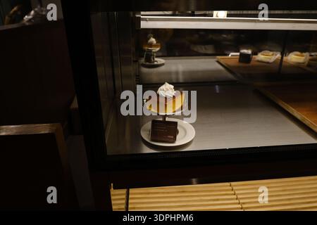 Una singola porzione di budino alla crema pasticcera giapponese con panna montata in una vetrina in un caffè di Komazawa Foto Stock