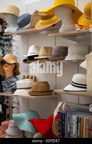 Esposizione colorata di cappelli estivi e alla moda sugli scaffali di un elegante negozio o boutique. Manichini, accessori e allestimenti organizzati per i cappelli creano Foto Stock