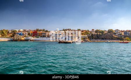 Panormos, Creta, Grecia - 9 settembre 2025: Vista costiera del villaggio di Panormos con porto, spiaggia e case tradizionali lungo la costa mediterranea Foto Stock