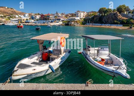 Panormos, Creta, Grecia - 9 settembre 2025: Piccole imbarcazioni ormeggiate nel porto di Panormos, con spiagge e case sul mare sullo sfondo. Foto Stock