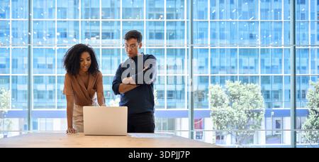 Due uomini d'affari impegnati che lavorano al computer discutono di un progetto al lavoro. Foto Stock