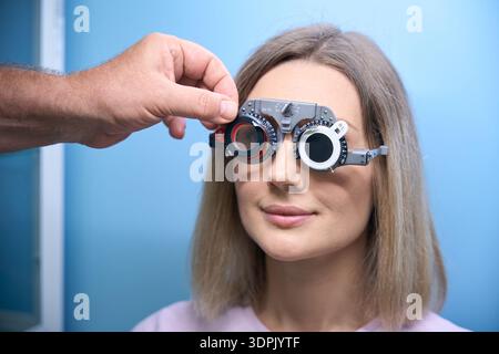 Giovane donna durante l'esame oculare prova occhiali occhiali di protezione presso la clinica ottica optometrista Foto Stock