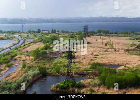 Pioggia pesante sulla città e le fabbriche dietro le linee elettriche sul campo Foto Stock