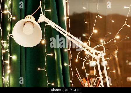 Atmosfera da studio serale con riflessi alla finestra, pennelli artistici e soft bokeh che creano un'atmosfera calda e intima Foto Stock
