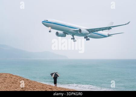 Viaggio di volo a Phuket in Thailandia durante la stagione delle piogge. Un aereo che vola in basso sul mare atterra all'aeroporto sull'isola, un turista in vacanza Foto Stock