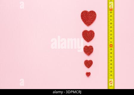 Sviluppare l'amore. Anniversario. Concetto emotivo. Scala d'amore. Anniversari di matrimonio d'oro e d'argento. spazio di scopia. cuori che crescono sul misuratore indicatina Foto Stock