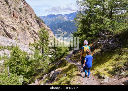 Vista posteriore di una madre con il bambino che cammina lungo un sentiero di montagna Foto Stock