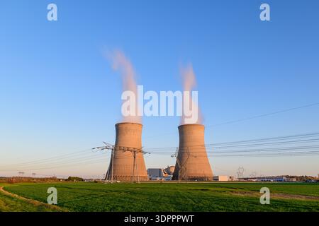 CNPE de Dampierre, Francia - 30 marzo 2021: Due grandi torri di raffreddamento che emettono vapore presso la centrale nucleare CNPE de Dampierre, con linee elettriche e campi verdi visibili in primo piano. Foto Stock