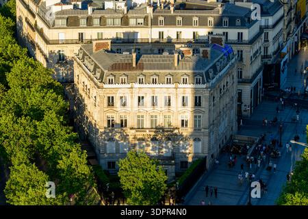 Parigi, Francia - 11 maggio 2022: Vista elevata di un hotel storico in Place de l'Etoile con la classica architettura parigina, circondato da strade alberate e pedoni visibili sotto alla luce del sole nel tardo pomeriggio. Foto Stock