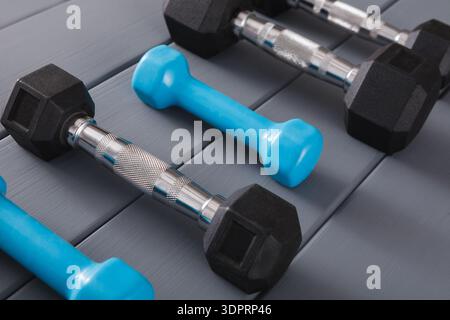 Vari pesi disposti su una superficie di legno in un ambiente fitness durante il giorno Foto Stock