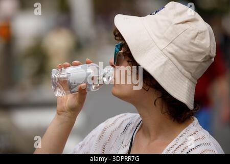 BANGKOK, TAILANDIA - 21 GENNAIO 2026: Turista femminile in cappello crema bere acqua da bottiglia, turista donna che esplora Wat Thai, profilo laterale, a Wat Arun. Foto Stock