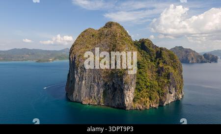 Vista aerea ad angolo di una ripida isola calcarea circondata da acque blu profonde, con pareti rocciose verticali e fitta vegetazione chiaramente visibile. Foto Stock