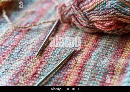 Confortevole scena di lavorazione a maglia fatta a mano con palline colorate in filato di lana e aghi in legno. Foto di alta qualità Foto Stock