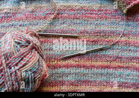 Confortevole scena di lavorazione a maglia fatta a mano con palline colorate in filato di lana e aghi in legno. Foto di alta qualità Foto Stock