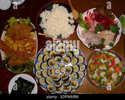 Delizioso e salutare sushi fatto a mano con makizushi crudo (sushi maki, sushi roll) e riso su un piatto su un tavolo in un ristorante in Giappone Foto Stock