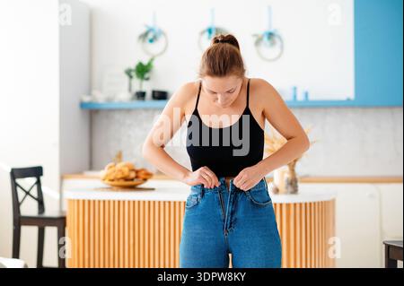 Una donna carina che stringe i jeans Foto Stock