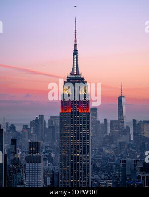 Vista aerea dell'Empire State Building immersa nel soffice bagliore del crepuscolo, in contrasto con l'oscuro skyline della città di New York, New York, Stati Uniti Foto Stock