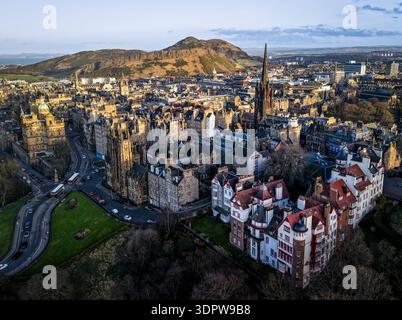 Vista aerea della luce dorata del sole che baciano le guglie storiche e i tetti della città vecchia, con l'iconico Arthur's Seat che incombe in lontananza, Edimburgo, Foto Stock