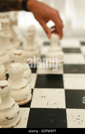 La mano di una persona che muove il pezzo degli scacchi su una tavola vintage Foto Stock