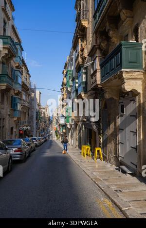 Strada in pendenza nella città di la Valletta a Malta, fiancheggiata da tradizionali case maltesi con balconi. Foto Stock
