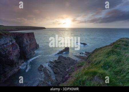 Spettacolare scogliera e macchia di mare al tramonto con un cielo scintillante sulla costa del Pembrokeshire, Galles. Foto Stock