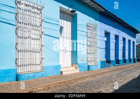 Case blu in stile coloniale con porte bianche e finestre a vista che fiancheggiano una strada acciottolata a Trinidad, Cuba Foto Stock