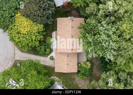 vista panoramica di una casa suburbana unifamiliare con tetto in ciottoli, vialetto privato e vialetto, circondata da alberi maturi e vegetazione. Foto Stock