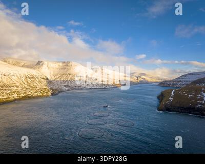 Veduta aerea delle serene acque blu che contrastano con le cime innevate di Drangarnir, creando un paesaggio mozzafiato, Drangarnir, Faroe ISL Foto Stock