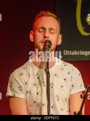 Babsea CD presentazione primo piano di un cantante che si esibisce dal vivo sul palco, occhi chiusi, canta nel microfono sotto una calda luce rossa Foto Stock
