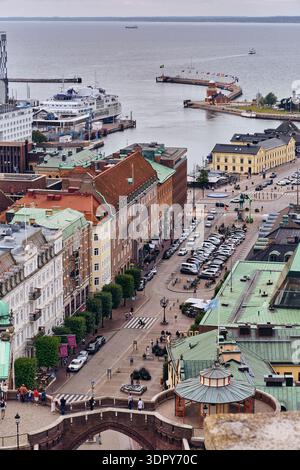 Helsingborg, Svezia - 12 agosto 2025: Veduta del paesaggio urbano dove i tetti di terracotta incontrano il mare, incorniciato dall'antico arco in pietra e dall'ar moderno Foto Stock