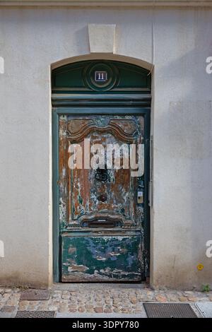 Porta in legno intemprata con vernice sbucciata su un edificio storico nella città vecchia di Avignone, Provenza-Alpi-Côte d'Azur, Francia. Foto Stock