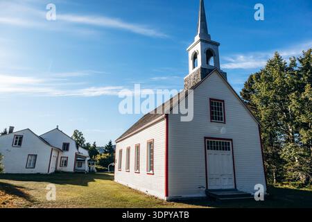 Edificio di chiesa in legno bianco presso il Village historique de Saint Firmin (villaggio storico di Saint Firmin), un sito storico conservato che rappresenta la tradizione Foto Stock