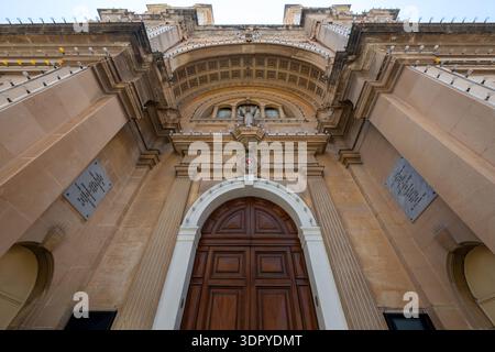 Vista dall'angolo basso della facciata della Chiesa Arcivescovile Stella Maris a Sliema, caratterizzata da una grande porta in legno, pilastri in pietra e soffitto portico ad arco Foto Stock