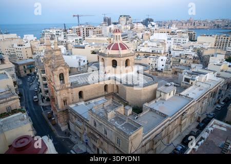Vista elevata della Chiesa Arcisacerdotale Stella Maris a Sliema, Malta, con campanile in pietra calcarea e cupola centrale circondata dalla densa città costiera buildi Foto Stock