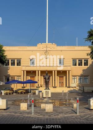 Statua di Dom Mintoff in una piazza lastricata con piccole fontane, posta davanti a una facciata simmetrica dell'edificio pubblico a la Valletta, Malta. Foto Stock