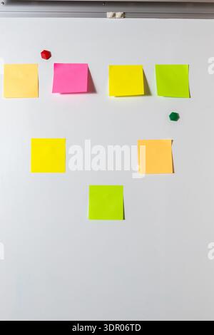 Sette note adesive bianche e colorate disposte su una superficie bianca. per brainstorming, pianificazione del team, promemoria, concetti e comunicazione Foto Stock