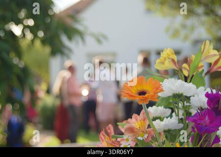 Bellissimo bouquet di fiori con un gruppo di persone sullo sfondo durante un evento all'aperto Foto Stock