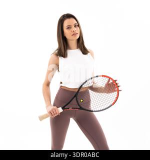 Una donna tiene in mano una racchetta da tennis e posa per un'immagine. Concetto di atletismo e fiducia, come la donna è vestita con abbigliamento atletico e io Foto Stock