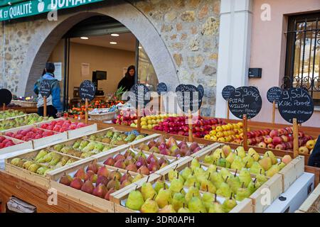 Pere e mele esposte all'esterno di un fruttivendolo a Valbonne, in Francia, con cartelli scritti a mano sui prezzi e sullo sfondo ad arco in pietra. Foto Stock