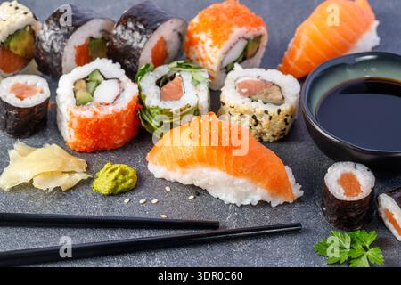 Sushi nigiri con salmone e caviale in primo piano. Set di sushi con salsa di soia, bacchette e prezzemolo su un tavolo di pietra. Foto Stock